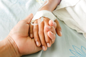 mother holding child's hand who fever patients have IV tube.